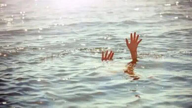 A person’s hands emerging from water in a canal, indicating a possible drowning incident.