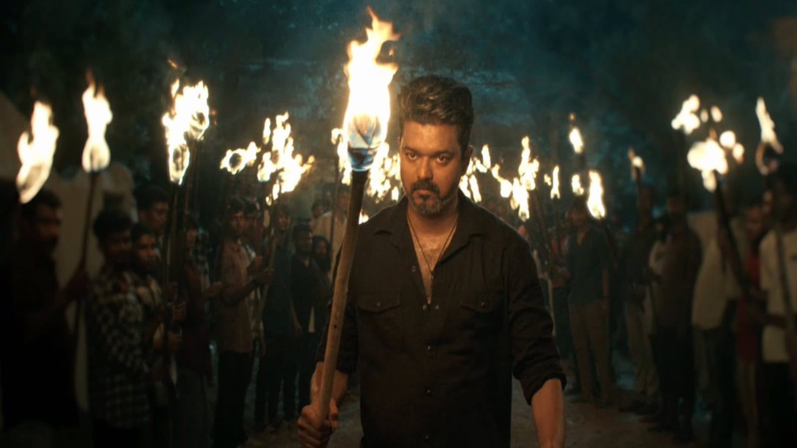 Vijay leads a torchlight march to address rumours, surrounded by supporters holding torches at night.