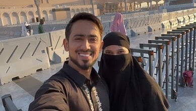 Happy couple taking a selfie at a mosque, celebrating conversion to Islam before marriage.