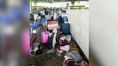 Kochi: Passengers wait below the flight information display at Cochin International Airport after several international flights were cancelled amid disruptions linked to the Iran-Israel conflict, in Kochi, Sunday, March 01, 2026. (PTI Photo)