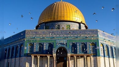 View of Al-Aqsa Mosque with golden dome and blue tile exterior in Jerusalem.