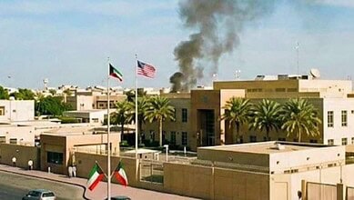 Black smoke rises near the US embassy compound in Kuwait as American and Kuwaiti flags fly outside the building.