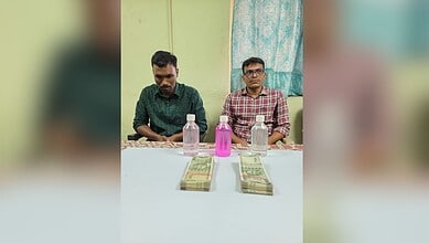 Two police officers caught taking a Rs 1 lakh bribe, with cash and bottles on the table, in Malkajgiri.