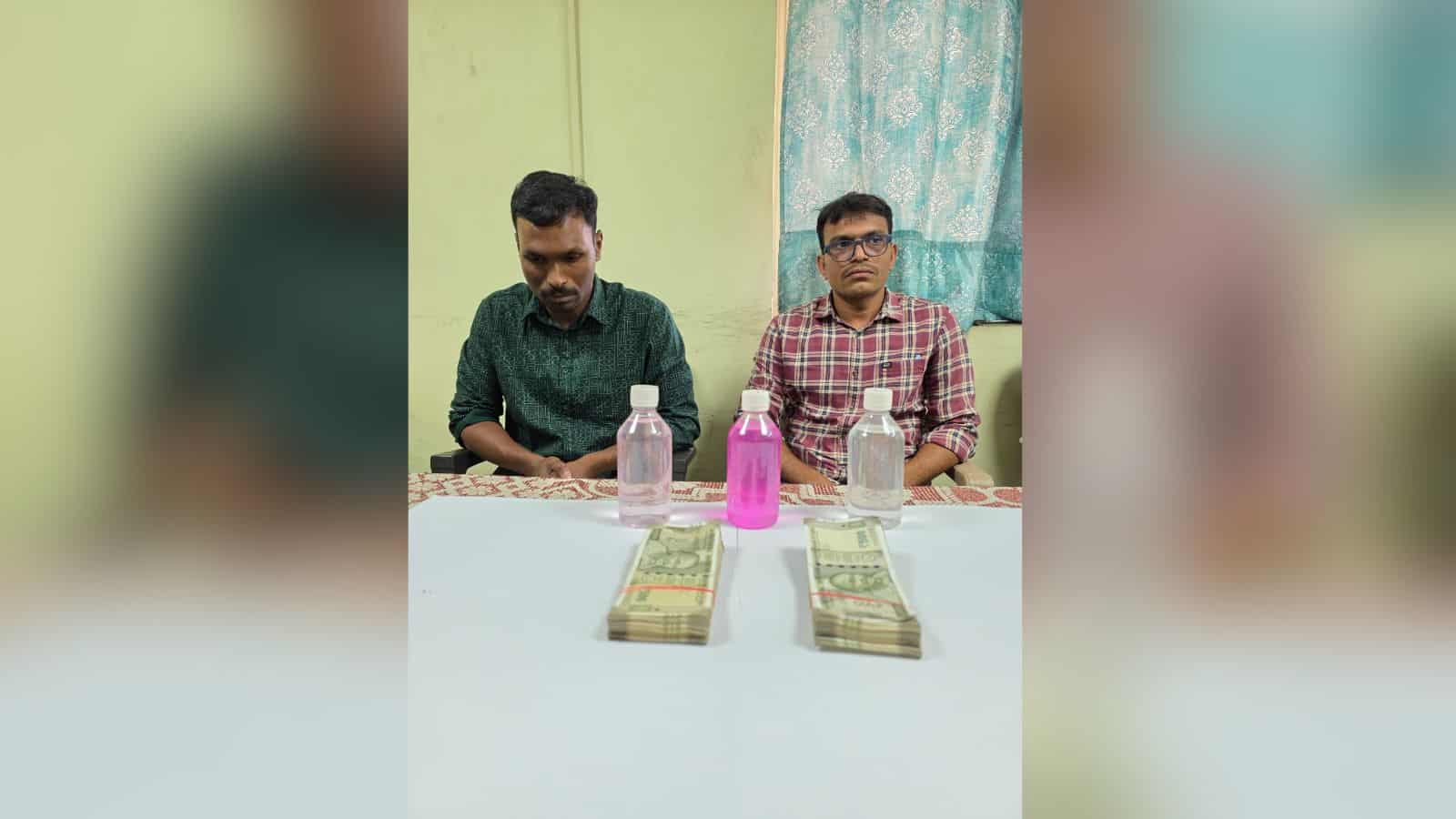 Two police officers caught taking a Rs 1 lakh bribe, with cash and bottles on the table, in Malkajgiri.