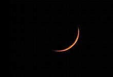 Crescent moon illuminated against a dark night sky, capturing a serene celestial scene.