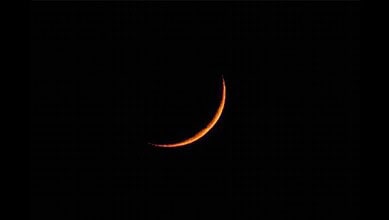 Crescent moon illuminated against a dark night sky, capturing a serene celestial scene.