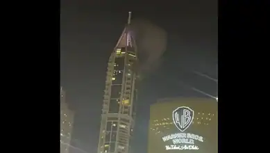 Night view of a tall building with smoke and bright lights during a conflict in Lebanon.