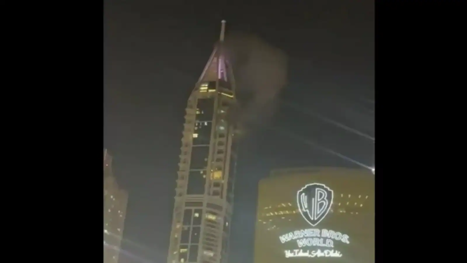 Night view of a tall building with smoke and bright lights during a conflict in Lebanon.