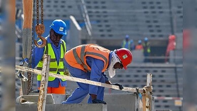 Workers on construction sites in Oman, wearing safety gear and helmets, involved in building infrastructu.