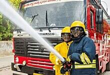 Firefighters training with a fire hose in front of a fire truck.