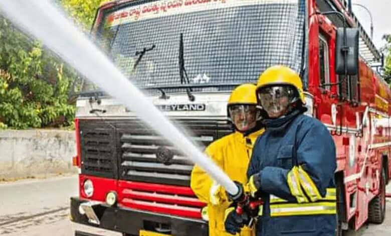 Firefighters training with a fire hose in front of a fire truck.
