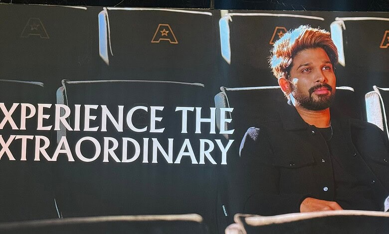 A man sitting in a cinema theatre with a backdrop displaying "Experience the Extraordinary" at Allu Cinem.