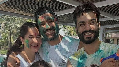 Group of friends celebrating Holi outdoors, covered in colourful powder, smiling and enjoying the festiva.