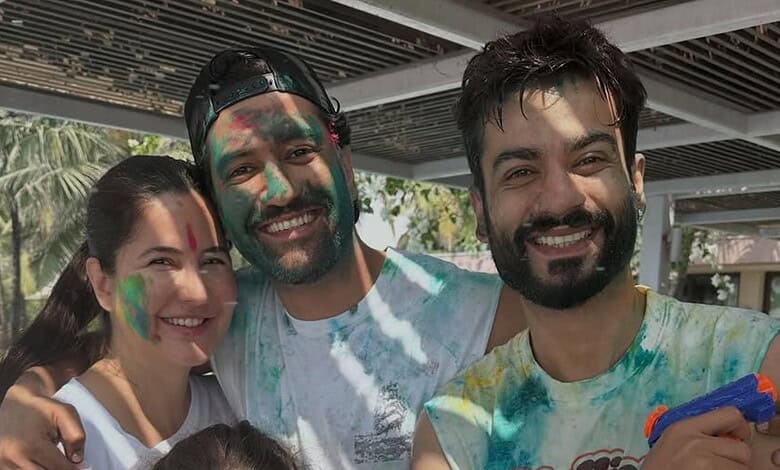 Group of friends celebrating Holi outdoors, covered in colourful powder, smiling and enjoying the festiva.