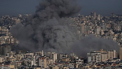 Explosion and smoke over a city skyline during ongoing conflict.