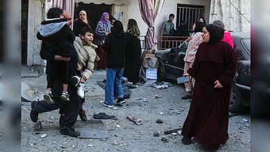 A man carries two children while residents flee after an Israeli strike hit a neighbourhood in Mieh Mieh near Sidon, Lebanon, on March 13, 2026.