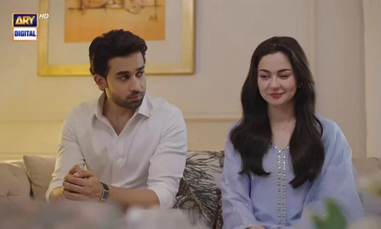 Two characters from Meri Zindagi Hai Tu episode 32 sitting on a sofa, smiling, in a cozy indoor setting.