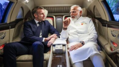 Indian Prime Minister Narendra Modi and French President Emmanuel Macron seated inside an car, engaged in conversation.