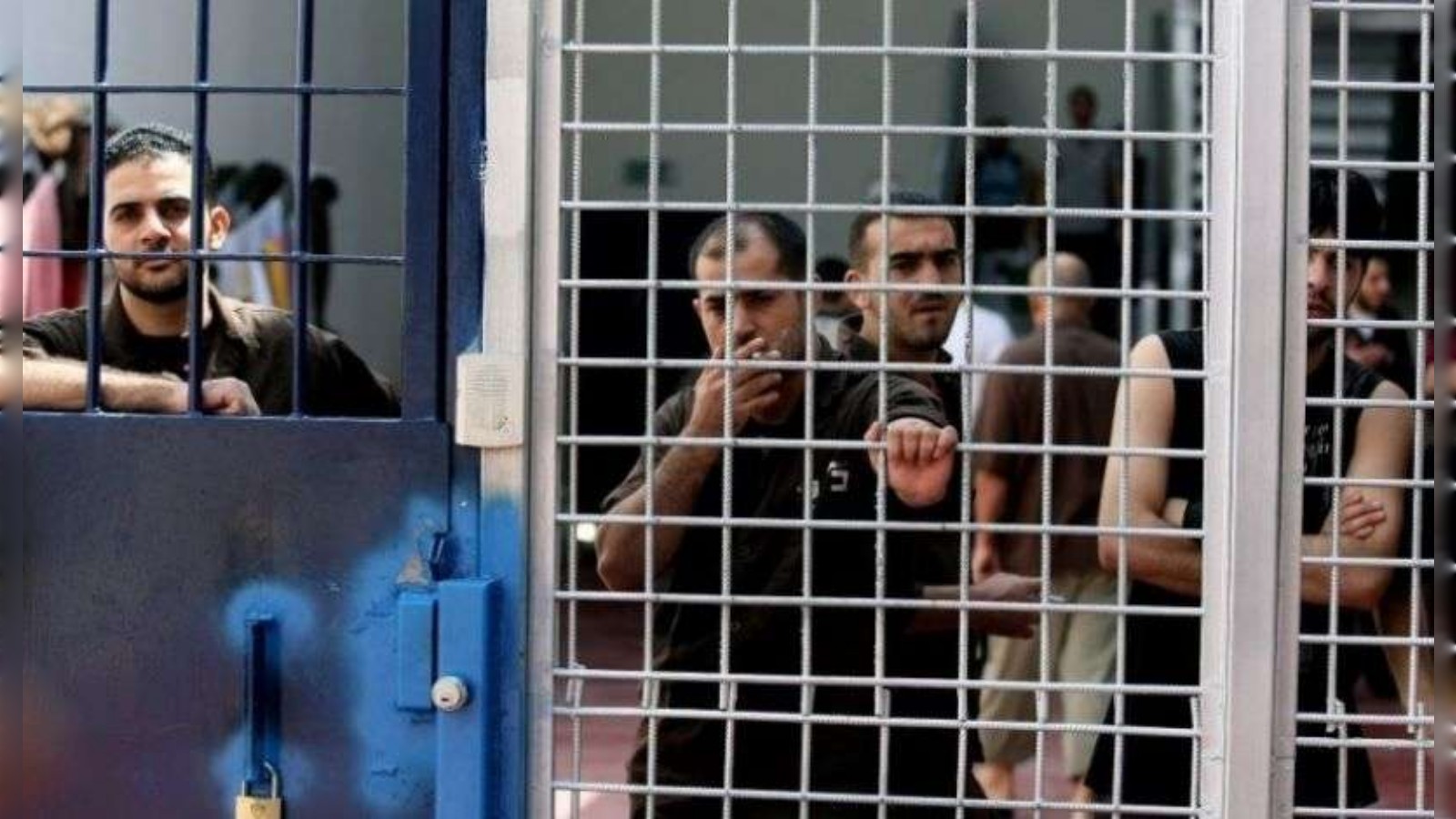 Palestinian prisoners seen behind metal bars inside a detention facility.