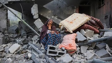 Woman and child sitting amid rubble and destruction in Gaza after an Israeli strike.