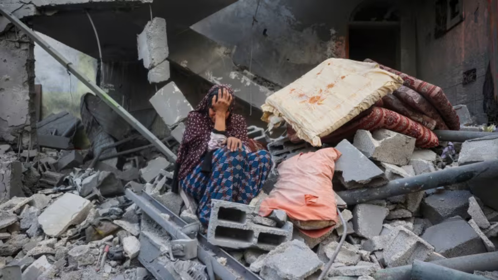 Woman and child sitting amid rubble and destruction in Gaza after an Israeli strike.