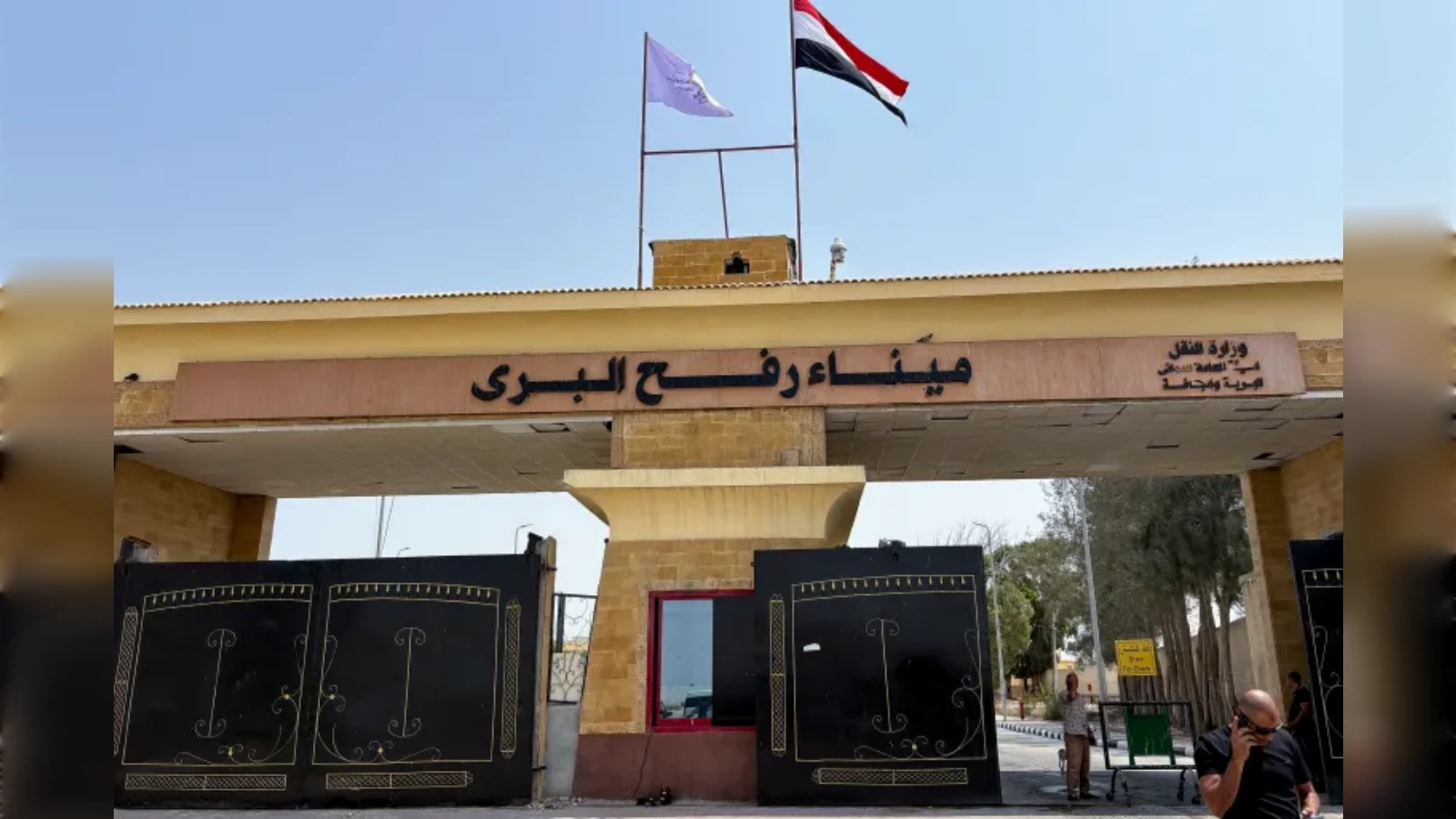 Egyptian side of Rafah border crossing gate with flags and security post.