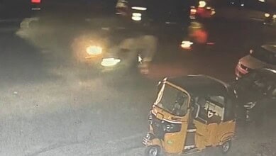 An auto rickshaw and vehicles on a street at night, with blurred lights and a smoky atmosphere, related t.