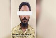 Man with a beard and dark hair, wearing a patterned shirt, facing the camera with a white bar covering hi.