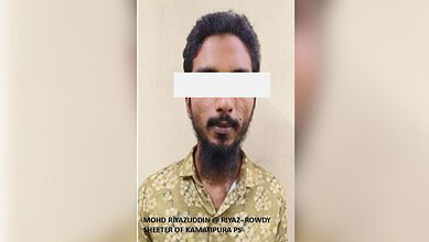 Man with a beard and dark hair, wearing a patterned shirt, facing the camera with a white bar covering hi.