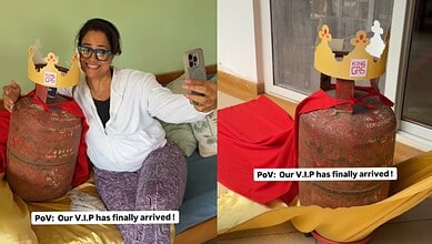 A woman holding a phone and smiling next to a large LPG cylinder with a humorous crown label, highlightin.