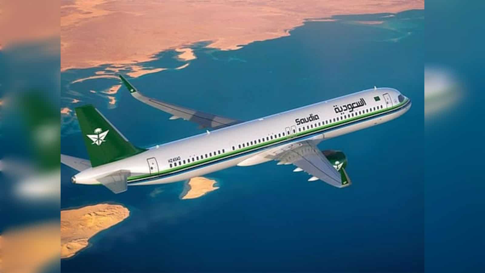 Saudia passenger aircraft flying over coastline during sunset.