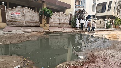 Flooded street with dug-up roads and residents raising alarm in Tolichowki.