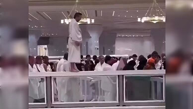 Umrah pilgrim praying on glass barrier inside Grand Mosque, security intervenes.