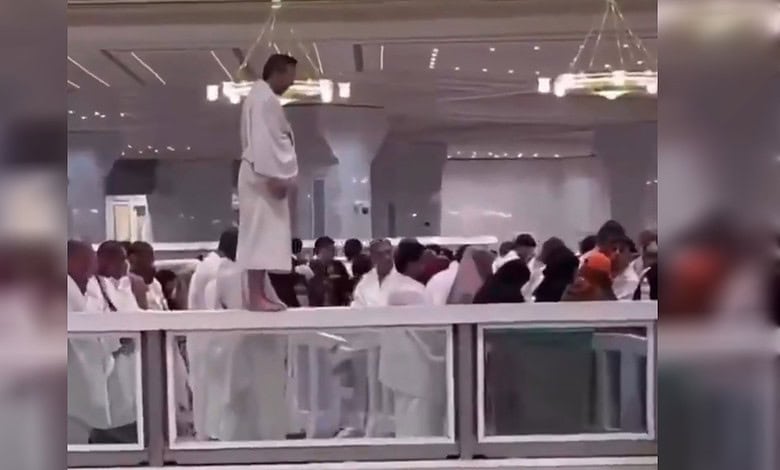 Umrah pilgrim praying on glass barrier inside Grand Mosque, security intervenes.
