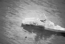 Warship navigating through ocean waters in a black and white image.