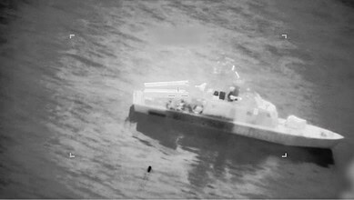 Warship navigating through ocean waters in a black and white image.