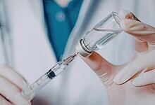 Image shows a healthcare worker drawing vaccine into a syringe, highlighting Covid vaccine administration and related policies.