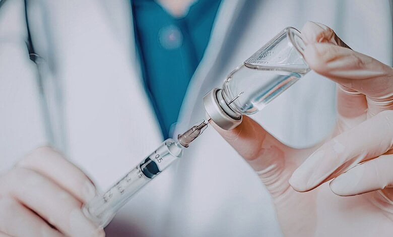 Image shows a healthcare worker drawing vaccine into a syringe, highlighting Covid vaccine administration and related policies.