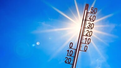 Bright sunny sky with a thermometer showing lower temperatures, symbolising relief from heat in Telangana.