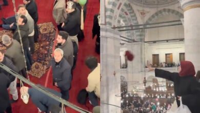 Woman throws headscarf from upper level during protest at Istanbul’s Fatih Mosque as men look on below.