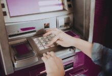 Image shows Person entering PIN on an ATM keypad