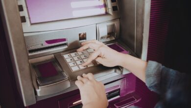 Image shows Person entering PIN on an ATM keypad