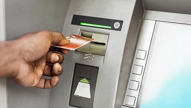 ATM card being inserted into a machine with a green light indicator.