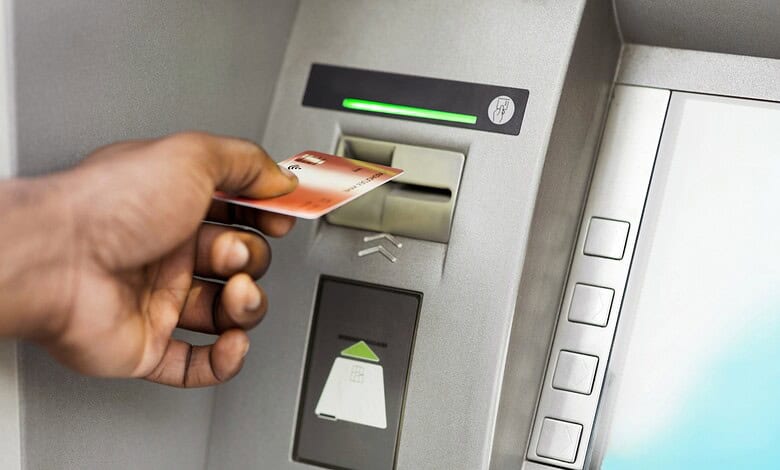 ATM card being inserted into a machine with a green light indicator.