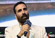 Akshay Kumar speaking into a microphone at a film event, discussing his role in Vanga and Dhar films.
