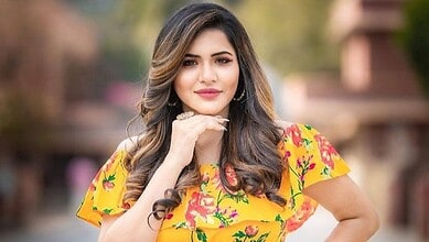 Ashu Reddy posing confidently outdoors, showcasing her vibrant attire and glamorous look.