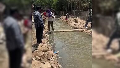 Locals crossing a nala in Banjara Hills using wooden planks during flood conditions.