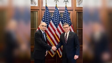 Two officials shaking hands in front of American flags during a terrorism exhibition on Capitol Hill.