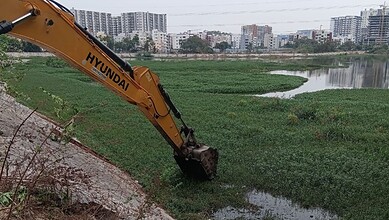 Excavator cleaning Hyderabad lake to prevent mosquito breeding and improve water quality.
