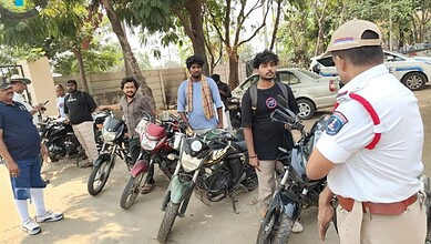 Police officer inspecting motorcycle number plates during vehicle regulation enforcement.
